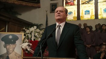 Movie still from “The Bucket List” (2007), directed by Rob Reiner – A man in a suit and tie standing in front of a microphone; Medium shot, Low angle