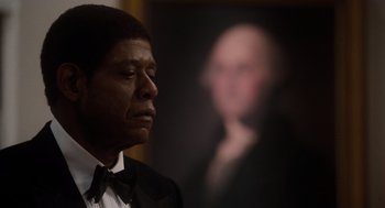 Movie still from “The Butler” (2013), directed by Lee Daniels – A man wearing a suit and tie in front of a picture of george washington; Close Up shot, Low angle