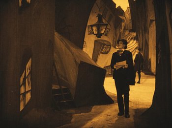 Movie still from “The Cabinet of Dr. Caligari” (1920), directed by Robert Wiene – A man in a suit is walking down the street; Wide shot, High angle