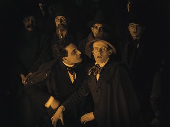 Movie still from “The Cabinet of Dr. Caligari” (1920), directed by Robert Wiene – A group of men standing next to each other in a dark room; Medium shot, High angle