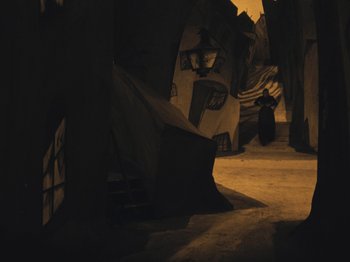 Movie still from “The Cabinet of Dr. Caligari” (1920), directed by Robert Wiene – A person is standing in the dark near a wall; Extreme Wide shot, High angle
