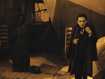 Movie still from “The Cabinet of Dr. Caligari” (1920), directed by Robert Wiene – A man dressed as a vampire standing next to a woman; Wide shot, Low angle