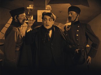 Movie still from “The Cabinet of Dr. Caligari” (1920), directed by Robert Wiene – A group of men standing next to each other holding umbrellas; Medium shot, Low angle