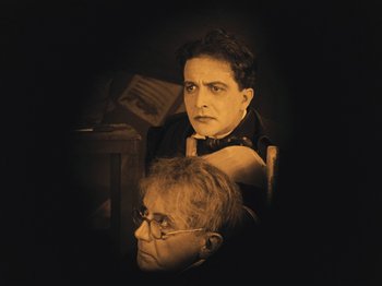 Movie still from “The Cabinet of Dr. Caligari” (1920), directed by Robert Wiene – A man and a woman sitting next to each other in a room; Medium shot, High angle