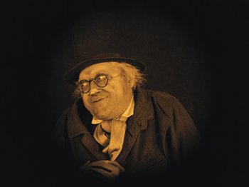 Movie still from “The Cabinet of Dr. Caligari” (1920), directed by Robert Wiene – An old man wearing glasses and a hat; Medium shot, Low angle
