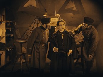 Movie still from “The Cabinet of Dr. Caligari” (1920), directed by Robert Wiene – A group of men standing next to each other in a room; Wide shot, High angle