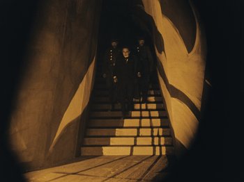 Movie still from “The Cabinet of Dr. Caligari” (1920), directed by Robert Wiene – A man standing on a set of stairs in the dark; Wide shot, High angle