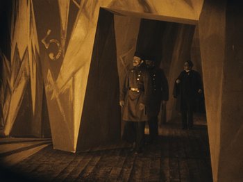Movie still from “The Cabinet of Dr. Caligari” (1920), directed by Robert Wiene – A group of men standing next to each other on a brick floor; Wide shot, High angle