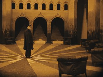Movie still from “The Cabinet of Dr. Caligari” (1920), directed by Robert Wiene – A man standing in the middle of an empty room; Extreme Wide shot, High angle