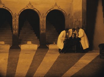 Movie still from “The Cabinet of Dr. Caligari” (1920), directed by Robert Wiene – A group of men in white robes are sitting on the ground; Extreme Wide shot, High angle