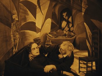 Movie still from “The Cabinet of Dr. Caligari” (1920), directed by Robert Wiene – A couple of people that are laying on the ground; Wide shot, High angle