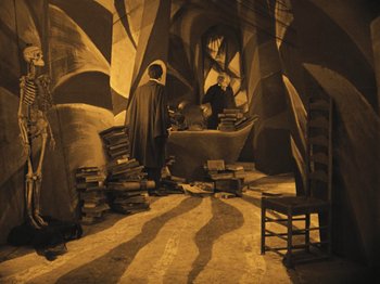 Movie still from “The Cabinet of Dr. Caligari” (1920), directed by Robert Wiene – Two people in a room with a tub and a chair; Wide shot, High angle