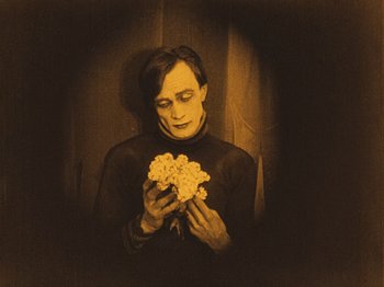 Movie still from “The Cabinet of Dr. Caligari” (1920), directed by Robert Wiene – A man holding a bunch of flowers in his hands; Medium shot, High angle