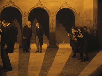 Movie still from “The Cabinet of Dr. Caligari” (1920), directed by Robert Wiene – A group of people standing around a building; Extreme Wide shot, High angle