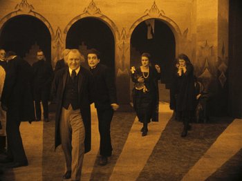 Movie still from “The Cabinet of Dr. Caligari” (1920), directed by Robert Wiene – A group of people are walking in a hallway together; Wide shot, High angle