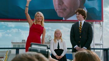 Movie still from “The Campaign” (2012), directed by Jay Roach – A woman in a red dress waves to the crowd; Medium shot, Low angle