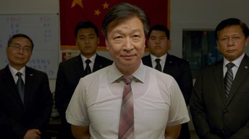 Movie still from “The Campaign” (2012), directed by Jay Roach – A man in a white dress shirt and a tie standing in front of two other men; Medium shot, Low angle