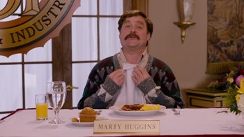 Movie still from “The Campaign” (2012), directed by Jay Roach – A man sitting at a dinner table with a plate of food in front of him; Medium shot, Over the shoulder angle