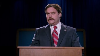 Movie still from “The Campaign” (2012), directed by Jay Roach – A man in a suit and tie at a podium; Medium shot, Low angle