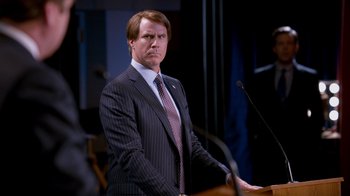Movie still from “The Campaign” (2012), directed by Jay Roach – A man standing at a podium in front of a microphone; Medium shot, Over the shoulder angle