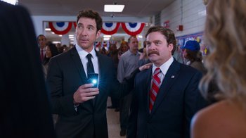 Movie still from “The Campaign” (2012), directed by Jay Roach – Two men in suits and ties holding a cell phone; Medium shot, Over the shoulder angle