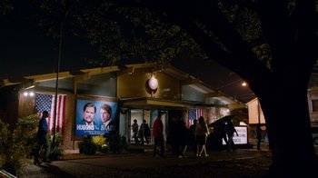 Movie still from “The Campaign” (2012), directed by Jay Roach – A group of people walking in front of a building at night; Extreme Wide shot, Low angle