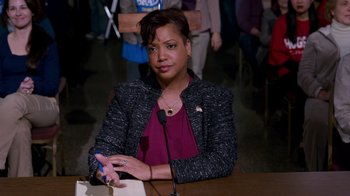 Movie still from “The Campaign” (2012), directed by Jay Roach – A person sitting at a table with a microphone; Medium shot, High angle
