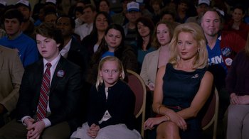 Movie still from “The Campaign” (2012), directed by Jay Roach – A group of people sitting in front of a crowd; Medium shot, Over the shoulder angle