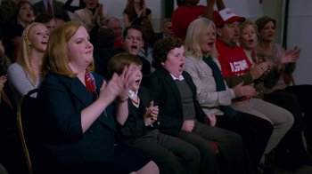 Movie still from “The Campaign” (2012), directed by Jay Roach – A group of people sitting in front of an audience; Medium shot, High angle