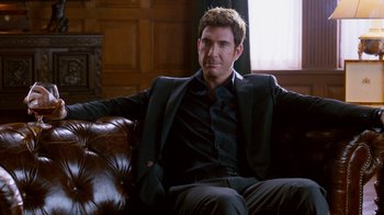 Movie still from “The Campaign” (2012), directed by Jay Roach – A man sitting on a leather chair in a room; Medium shot, Over the shoulder angle