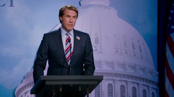 Movie still from “The Campaign” (2012), directed by Jay Roach – A man in a suit standing at a podium in front of a building; Medium shot, Low angle