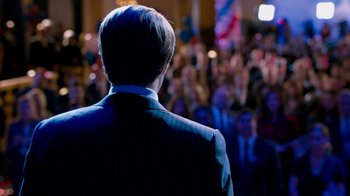 Movie still from “The Campaign” (2012), directed by Jay Roach – A man standing in front of a crowd of people; Medium shot, Over the shoulder angle