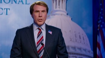 Movie still from “The Campaign” (2012), directed by Jay Roach – A man in a suit and tie standing in front of a microphone; Medium shot, Over the shoulder angle