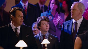 Movie still from “The Campaign” (2012), directed by Jay Roach – A group of people standing in a room; Medium shot, Over the shoulder angle