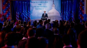 Movie still from “The Campaign” (2012), directed by Jay Roach – A crowd of people standing in front of a large screen; Extreme Wide shot, High angle