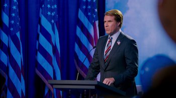 Movie still from “The Campaign” (2012), directed by Jay Roach – A man standing at a podium in front of american flags; Medium shot, Low angle