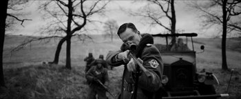 Movie still from “The Captain” (2017), directed by Robert Schwentke – A man taking a picture of a group of soldiers; Medium shot, Over the shoulder angle