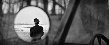 Movie still from “The Captain” (2017), directed by Robert Schwentke – A man in a uniform looking out of a car mirror; Medium shot, Over the shoulder angle