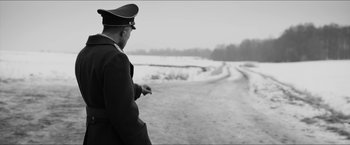 Movie still from “The Captain” (2017), directed by Robert Schwentke – A man in a military uniform standing on the side of a road; Medium shot, Over the shoulder angle