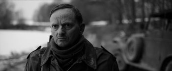 Movie still from “The Captain” (2017), directed by Robert Schwentke – Black and white photograph of a man in a jacket and scarf; Close Up shot, Over the shoulder angle