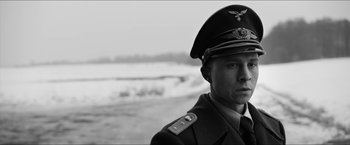 Movie still from “The Captain” (2017), directed by Robert Schwentke – A man in a military uniform standing in front of a body of water; Close Up shot, Low angle