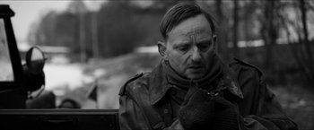 Movie still from “The Captain” (2017), directed by Robert Schwentke – An older man sitting on top of a wooden bench; Close Up shot, Over the shoulder angle