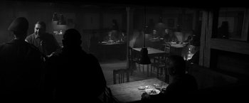 Movie still from “The Captain” (2017), directed by Robert Schwentke – People are sitting at a table in a dark room; Wide shot, High angle