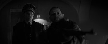 Movie still from “The Captain” (2017), directed by Robert Schwentke – A man and a woman standing next to each other in a dark room; Close Up shot, Over the shoulder angle