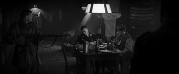 Movie still from “The Captain” (2017), directed by Robert Schwentke – Two men sitting at a dinner table in a dimly - lit room; Wide shot, High angle