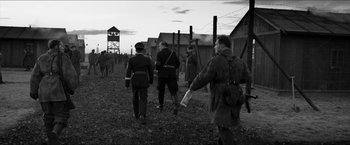Movie still from “The Captain” (2017), directed by Robert Schwentke – A black and white photo of a group of men in uniform; Wide shot, Over the shoulder angle