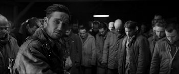 Movie still from “The Captain” (2017), directed by Robert Schwentke – Black and white photograph of a group of people in a dark room; Medium shot, Over the shoulder angle