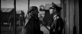 Movie still from “The Captain” (2017), directed by Robert Schwentke – Two men in military garb talking to each other; Medium shot, Over the shoulder angle