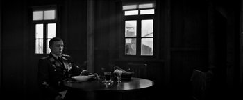 Movie still from “The Captain” (2017), directed by Robert Schwentke – A black and white photo of a table and a window; Wide shot, Over the shoulder angle