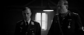 Movie still from “The Captain” (2017), directed by Robert Schwentke – Two men in military uniforms standing next to each other in front of a window; Medium shot, Low angle